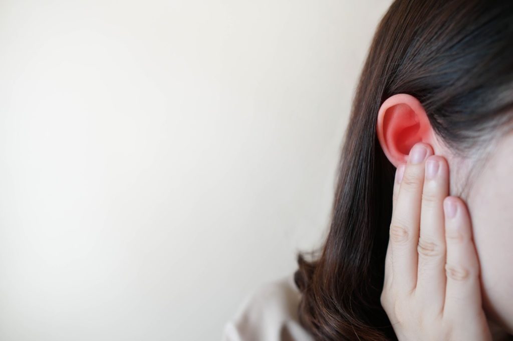 female holding her ear in pain