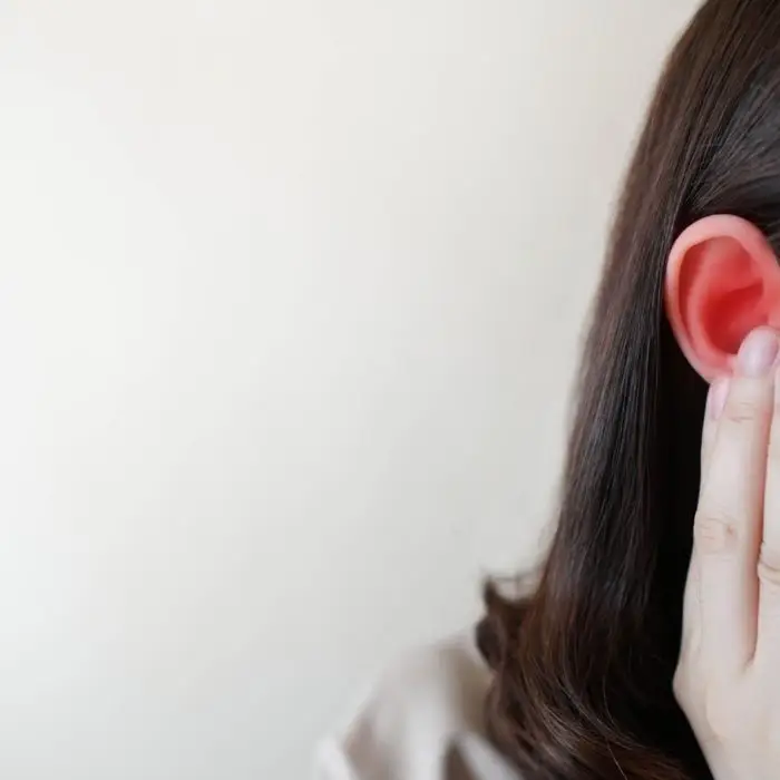 female holding her ear in pain