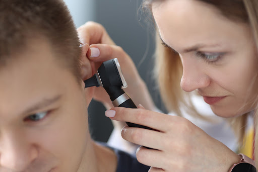 woman inspecting young man's ear with otoscopeman's ear with