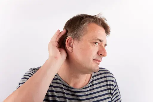 man with hand around ear